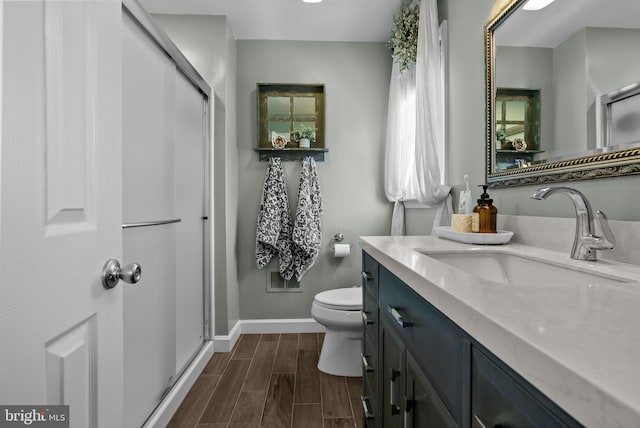 bathroom with vanity, baseboards, a stall shower, and wood finish floors
