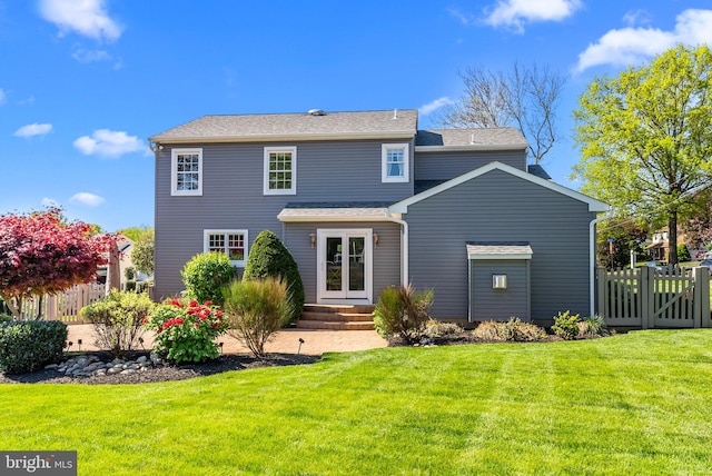 back of property with fence, a yard, and french doors