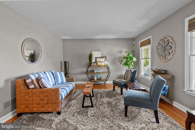 living area featuring baseboards, visible vents, and wood finished floors