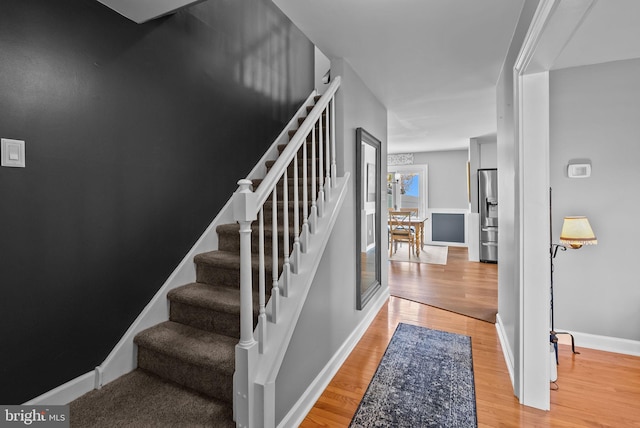 staircase with baseboards and wood finished floors