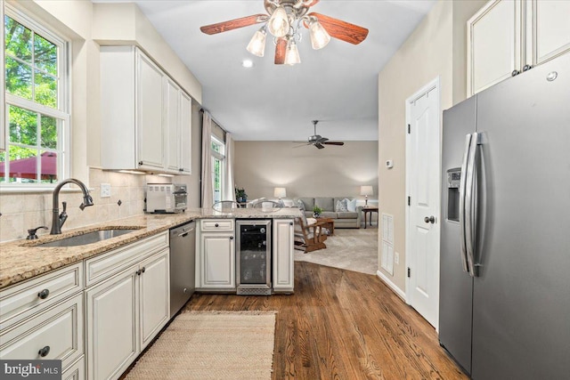 kitchen featuring a ceiling fan, beverage cooler, dark wood-style floors, a sink, and stainless steel appliances