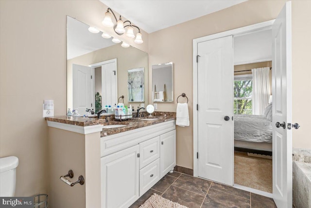 bathroom featuring connected bathroom, double vanity, toilet, and a sink