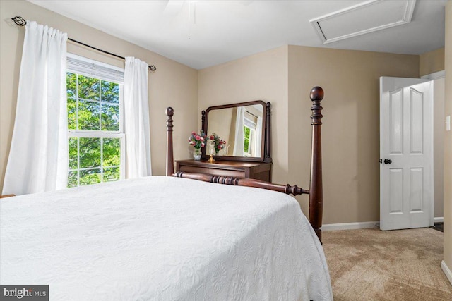 bedroom with light colored carpet, a ceiling fan, baseboards, and attic access
