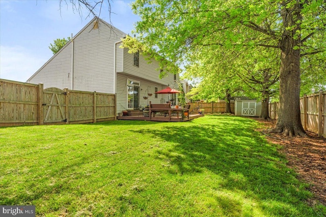view of yard with a fenced backyard, an outbuilding, a storage shed, and a deck
