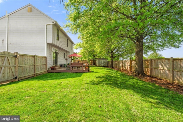 view of yard with a fenced backyard, a storage unit, a wooden deck, and an outdoor structure