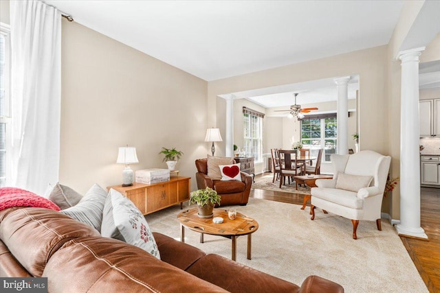 living room with ceiling fan, ornate columns, and wood finished floors