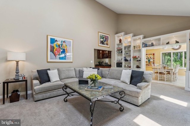 carpeted living room with high vaulted ceiling and baseboards