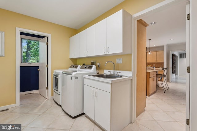 clothes washing area featuring separate washer and dryer, a sink, cabinet space, and light tile patterned flooring
