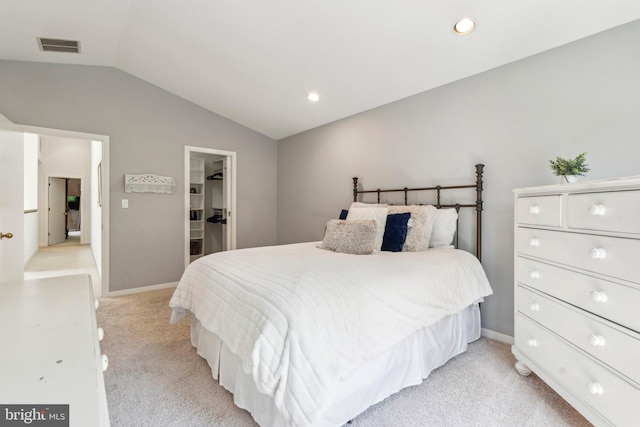 bedroom featuring a walk in closet, visible vents, baseboards, lofted ceiling, and light carpet
