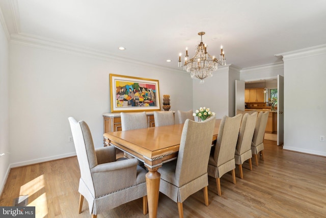 dining space with light wood-style floors, ornamental molding, baseboards, and a chandelier