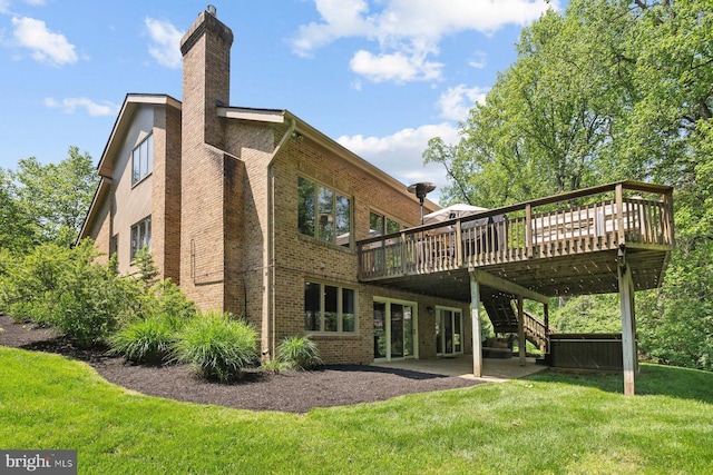 back of property featuring a deck, a chimney, brick siding, a lawn, and stairway