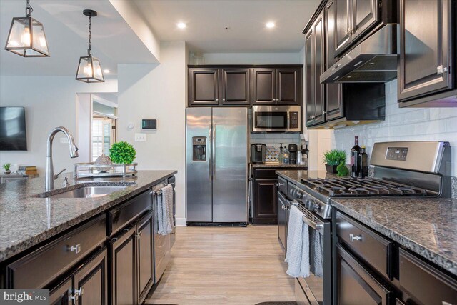 5735 River Shark Ln, Waldorf, MD 20602 - kitchen featuring stainless steel appliances, a sink, under cabinet range hood, dark brown cabinetry, and dark stone countertops