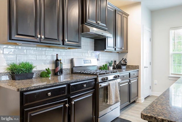 5735 River Shark Ln, Waldorf, MD 20602 - kitchen with stainless steel range with gas cooktop, under cabinet range hood, light wood-style floors, decorative backsplash, and dark stone counters