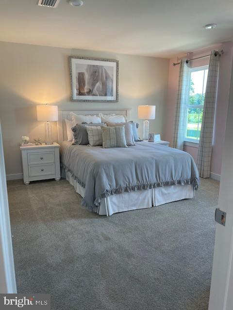 bedroom featuring visible vents, light carpet, and baseboards