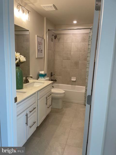 bathroom featuring visible vents, tub / shower combination, toilet, vanity, and tile patterned flooring
