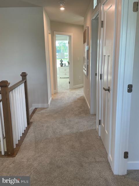 hallway featuring an upstairs landing, carpet, and baseboards