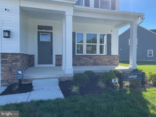 property entrance with covered porch and stone siding