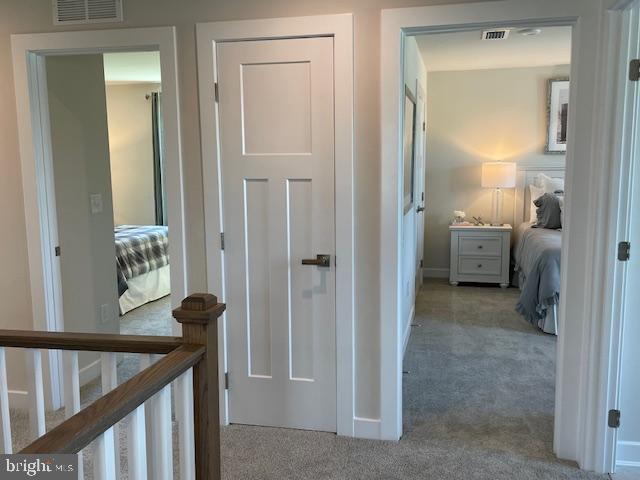 hall featuring carpet flooring, baseboards, and visible vents