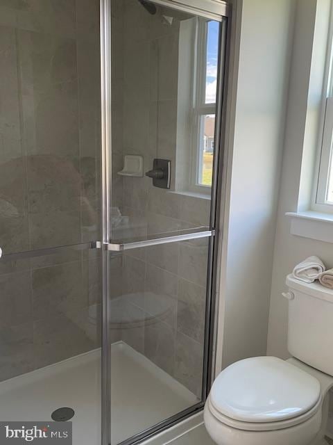 bathroom featuring a stall shower and toilet