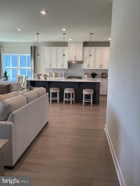 living area featuring wood finished floors, recessed lighting, and baseboards