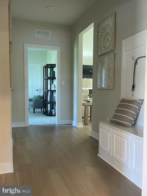 hallway featuring wood finished floors, visible vents, and baseboards