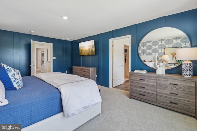 bedroom featuring carpet, a decorative wall, and visible vents