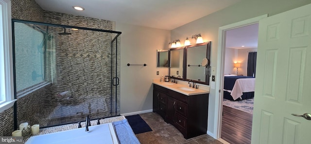 full bathroom with connected bathroom, double vanity, a sink, baseboards, and a stall shower