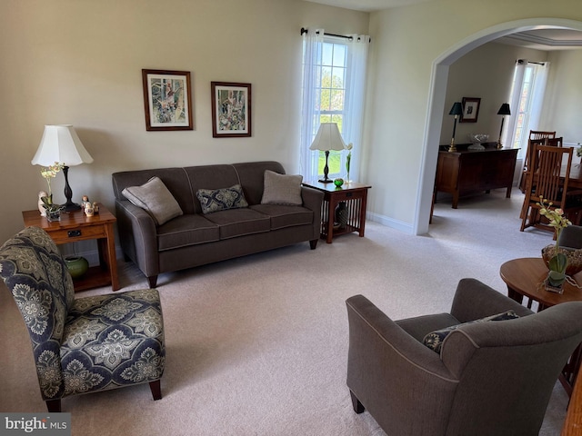 carpeted living room with arched walkways and baseboards