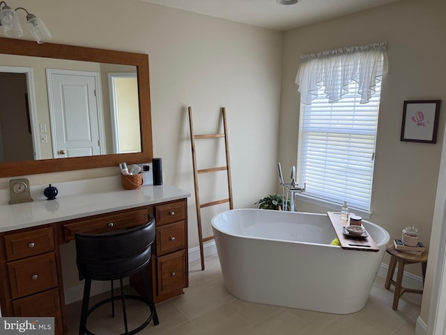 bathroom featuring vanity, a freestanding bath, tile patterned flooring, and baseboards
