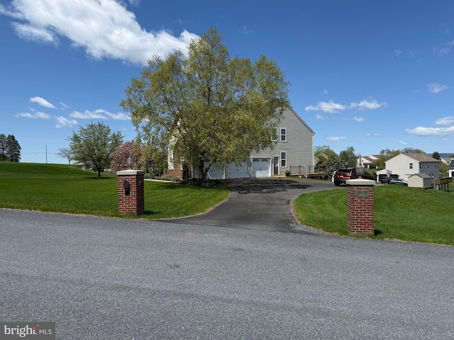 view of property hidden behind natural elements with a front yard, driveway, and a garage