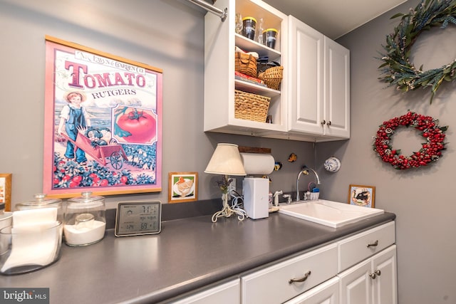 interior space featuring a sink, dark countertops, white cabinets, and open shelves