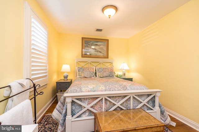 bedroom featuring visible vents, baseboards, and wood finished floors