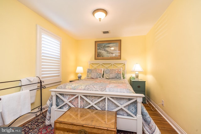 bedroom featuring baseboards, wood finished floors, and visible vents
