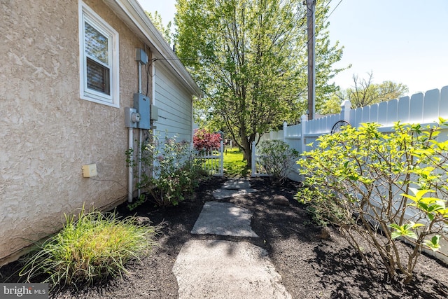 view of side of home featuring fence and stucco siding