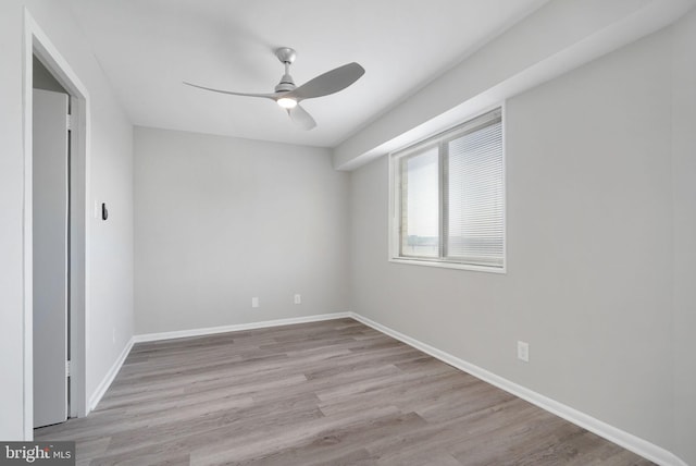 spare room with wood finished floors, ceiling fan, and baseboards