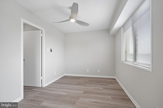 spare room featuring baseboards, ceiling fan, and light wood-style floors