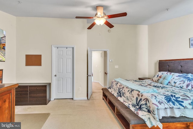 bedroom with a ceiling fan, baseboards, light colored carpet, and a towering ceiling
