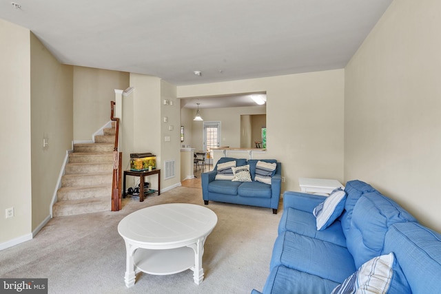 living area with stairs, baseboards, visible vents, and carpet