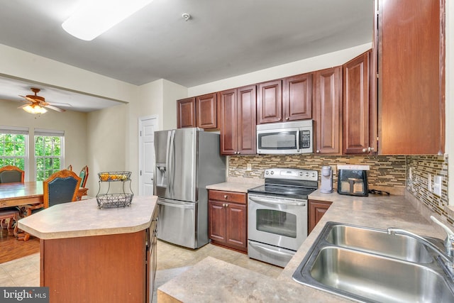 kitchen with a ceiling fan, backsplash, a sink, light countertops, and stainless steel appliances