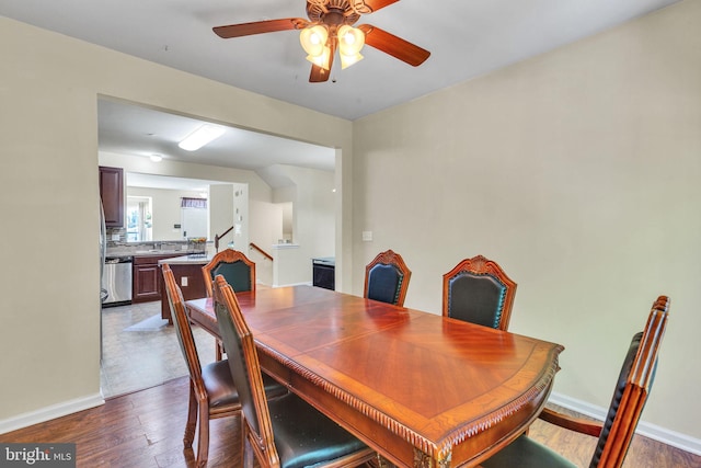 dining space with baseboards, ceiling fan, dark wood-style flooring, and stairs