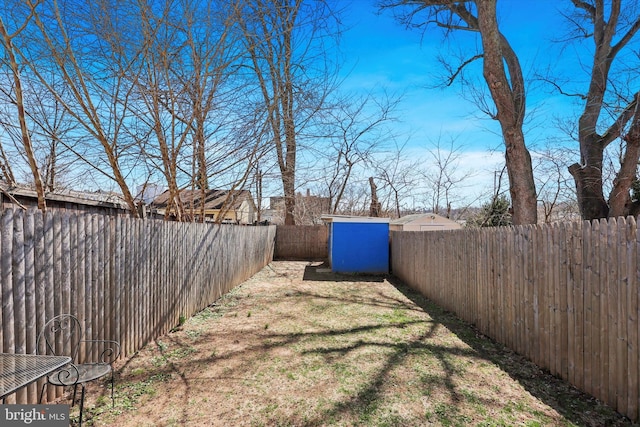 view of yard featuring an outdoor structure, a shed, and a fenced backyard