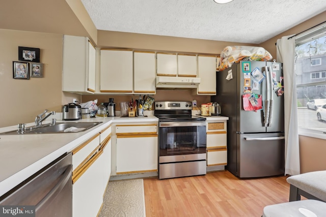 1660 Thenia Pl, Woodbridge, VA 22192 - kitchen featuring appliances with stainless steel finishes, a sink, light countertops, under cabinet range hood, and light wood-style flooring