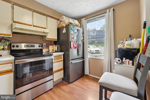 1660 Thenia Pl, Woodbridge, VA 22192 - kitchen with light wood-type flooring, light countertops, a textured ceiling, under cabinet range hood, and stainless steel appliances