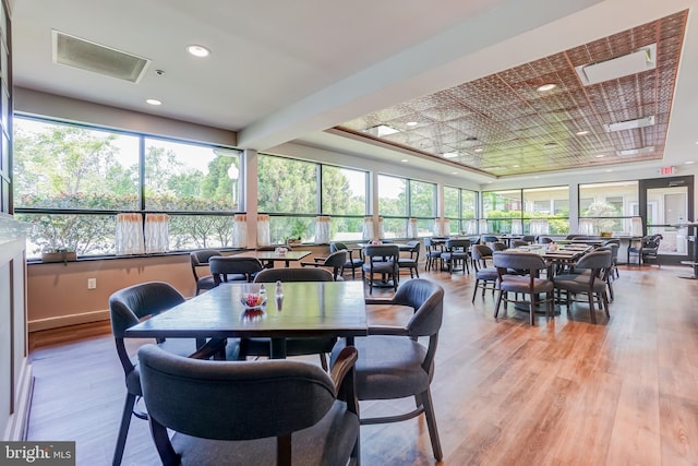 dining space with plenty of natural light, a tray ceiling, and light wood finished floors