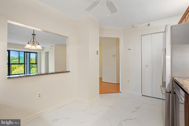 interior space with baseboards, ceiling fan with notable chandelier, a textured ceiling, and marble finish floor