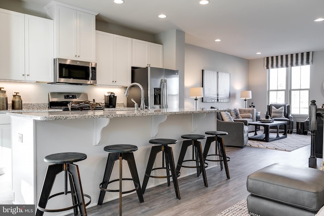 kitchen featuring recessed lighting, light wood finished floors, white cabinets, and stainless steel appliances
