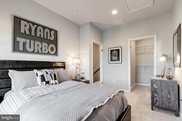 bedroom featuring a closet, baseboards, attic access, light carpet, and a walk in closet