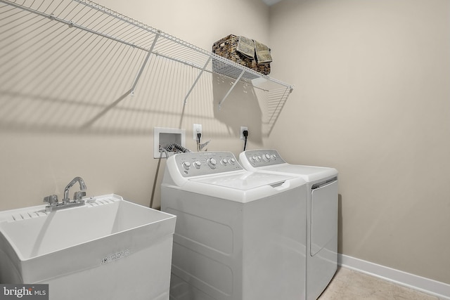 clothes washing area featuring laundry area, tile patterned floors, washing machine and dryer, baseboards, and a sink