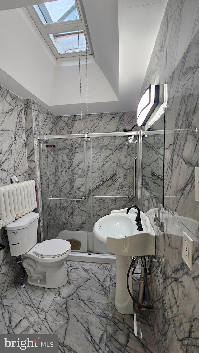 full bath with toilet, a marble finish shower, marble finish floor, tile walls, and a skylight