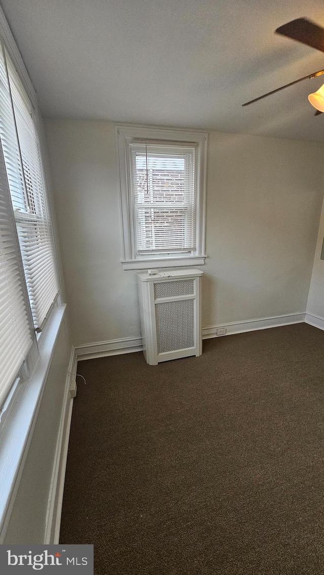 spare room with a healthy amount of sunlight, carpet floors, baseboards, and a ceiling fan